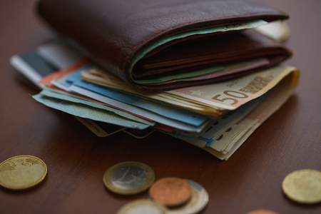 59796361-cartera-de-cuero-marrón-con-el-dinero-euro-por-dentro-y-por-monedas-tarjetas-de-crédito-cerca-de
